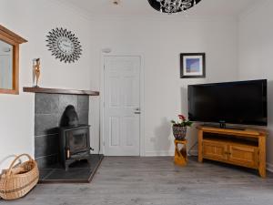 a living room with a fireplace and a flat screen tv at Ards House Self catering apartment with sea views in Oban