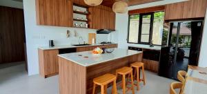 a kitchen with wooden cabinets and a island with bar stools at Rancho Relaxo Pool Villa in Ban Tai