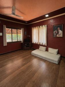a bedroom with a bed in a room with wooden floors at Mangalmurti Farmstay in Pendur +14 photos
