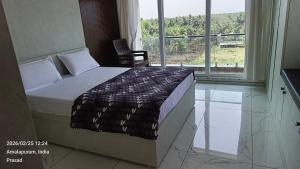 a bedroom with a bed and a large window at Suneetha Presidency in Amalāpuram