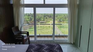 a bedroom with a large window with a chair and a view at Suneetha Presidency in Amalāpuram