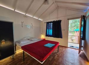 a bedroom with a bed with a red blanket at Bhakti Yoga Ashram in Canacona