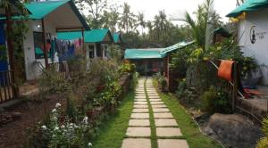 a walkway through a garden with houses at Bhakti Yoga Ashram in Canacona