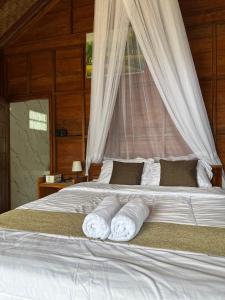 a bedroom with a bed with towels on it at Kubu Waru Bali in Munduk