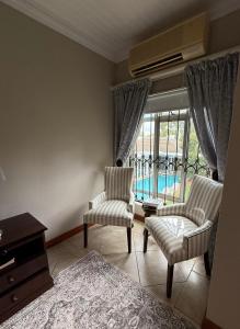 a living room with two chairs and a window at ARK Guesthouse in Potchefstroom
