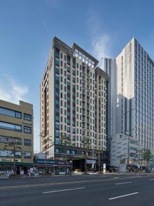 two tall buildings in a city with a street at Western Coop Hotel & Residence Dongdaemun in Seoul