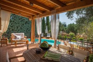 a patio with a table and chairs and a pool at Anassa Villa in Mouzákion
