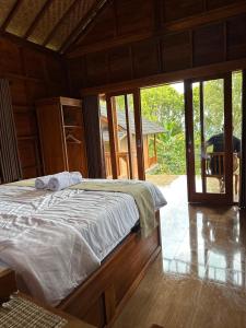 a bedroom with a bed in a room with glass doors at Kubu Waru Bali in Munduk +42 photos