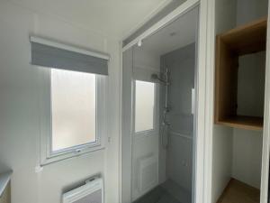 a bathroom with a walk in shower and a window at CAMPING Les EMBRUNS - 4 ETOILES in Lège-Cap-Ferret