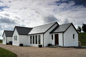 a white house with a black roof at Hartaval & Baca Ruadh in Staffin