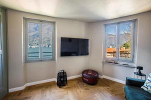 a living room with three windows and a flat screen tv at Il Giardino di Nesso in Nesso