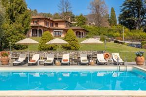 ein Pool mit Stühlen und Sonnenschirmen vor einem Haus in der Unterkunft Hotel Royal in Menaggio