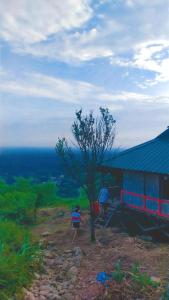 a person standing next to a tree next to a building at Nature's Harmony Heaven in Dāmbuk +2 photos
