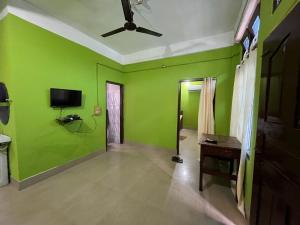 a living room with green walls and a ceiling fan at Anigo Cottage Naharlagun in Bacha