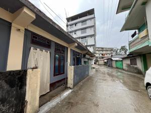 an empty street with a building and a car parked next to it at Anigo Cottage Naharlagun in Bacha