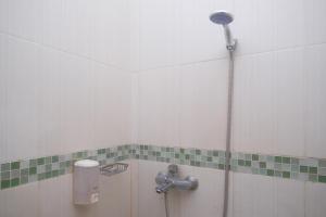 a shower in a bathroom with green and white tiles at RedDoorz Plus @ Timoho in Yogyakarta +31 photos