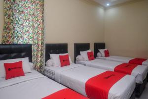 three beds in a room with red and white pillows at RedDoorz Plus @ Timoho in Yogyakarta