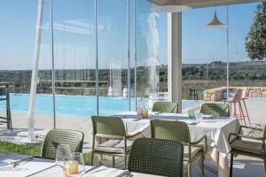 ein Restaurant mit Tischen und Stühlen und einem Pool in der Unterkunft Methe in Lizzano