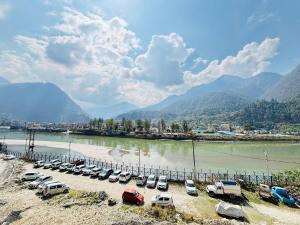 a group of cars parked in a parking lot next to a river at The HIGHLIGHT STAY in Uttarkāshi