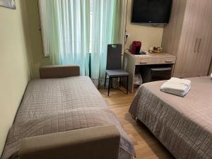 a hotel room with two beds and a desk and a television at A Casuzza in Pollina