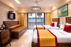 a hotel room with two beds and a television at West End Hotel Opp Bombay Hospital in Mumbai +120 photos