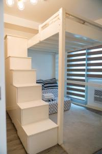 a white bunk bed with stairs in a bedroom at Relaxing Mountain View 2BR Fast WiFi and PS5 in Manila +13 photos