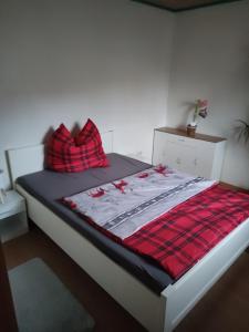 a bed with a red blanket and pillows on it at Ferienwohnung Mandy in Morsleben