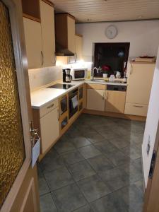a kitchen with white cabinets and a tile floor at Ferienwohnung Mandy in Morsleben