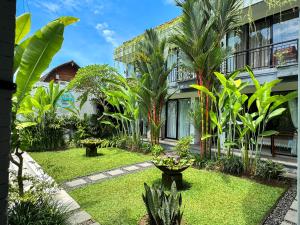 a garden in front of a building with palm trees at The Palms Canggu in Canggu