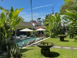 a pool with chairs and umbrellas in a garden at The Palms Canggu in Canggu