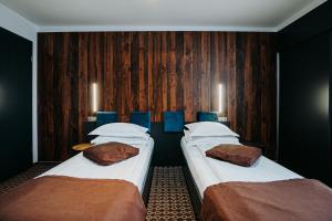 two beds in a room with wooden walls at Pension Belascu in Sibiu +35 photos