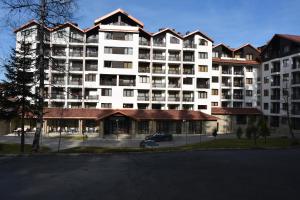 ein großes weißes Apartmenthaus mit Parkplatz in der Unterkunft Borovets Holiday Apartments - Different Locations in Borovets in Borowez