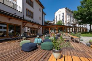 eine Holzterrasse mit Stühlen und Tischen an einem Gebäude in der Unterkunft Hotel Schweizerhof Lenzerheide in Lenzerheide