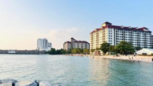 a beach with buildings and people on the beach at Glory Beach Resort By D'Shepherd Management in Port Dickson