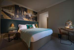 a bedroom with a large bed with a painting on the wall at Harper's Steakhouse with Rooms, Haslemere in Haslemere