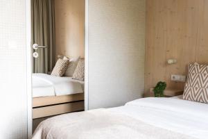 a bedroom with two beds and a mirror at Hotel Bergamo Modern & zentral in Ludwigsburg 24h Check in 3 Min zum Schloss nachhaltiges Hotel in Holzbauweise in Ludwigsburg
