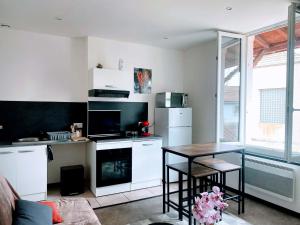 a kitchen with white cabinets and a table in it at L'escale Urbaine avec fibre internet 4 pers Confort & Emplacement Idéal in Marmande