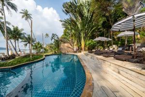 a swimming pool with lounge chairs and the ocean at Tolani Resort Koh Kood in Ko Kood