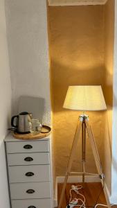 a lamp with a tripod next to a dresser at Les chambres de la Bastide in Saint-Sauveur-de-Montagut
