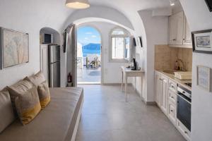 a kitchen with a couch and a kitchen with an open door at Yposkafo Suites - Studio - Santorini in Fira