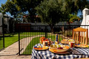 a picnic table with plates of food on top of it at Far Far Away Guesthouse - 4-star Luxury Karoo Escape with Garden, Pool & Personal Touch in Graaff-Reinet +32 photos