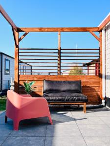 a bench and a pink chair on a patio at B&B Voor De Zee in Westerland