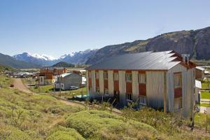 une maison sur une colline avec des montagnes en arrière-plan dans l'établissement Hosteria Alma de Patagonia, à El Chalten