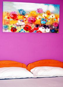 une peinture de fleurs sur un mur violet au-dessus d'un lit dans l'établissement B&B Federico II, à San Cipirello