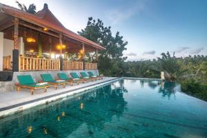 a swimming pool with green lounge chairs next to a house at Green Coco Suite by AGATA in Nusa Penida