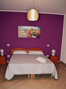 a bedroom with a bed with a purple wall at B&B Federico II in San Cipirello