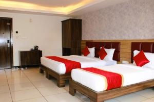 a hotel room with two beds with red pillows at Mayuri Residency BTM Layout in Bangalore