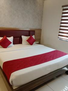 a bed with red and white pillows in a room at Mayuri Residency BTM Layout in Bangalore