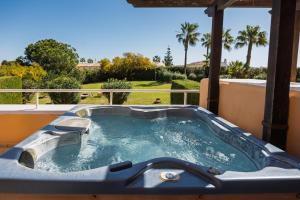 a jacuzzi tub on a balcony with palm trees at Malibu Mansions by the beach by ALFRESCO STAYS in Mijas Costa