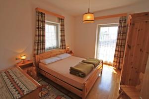 a bedroom with a bed and two windows at Tony Sport appartamenti in Vigo di Fassa